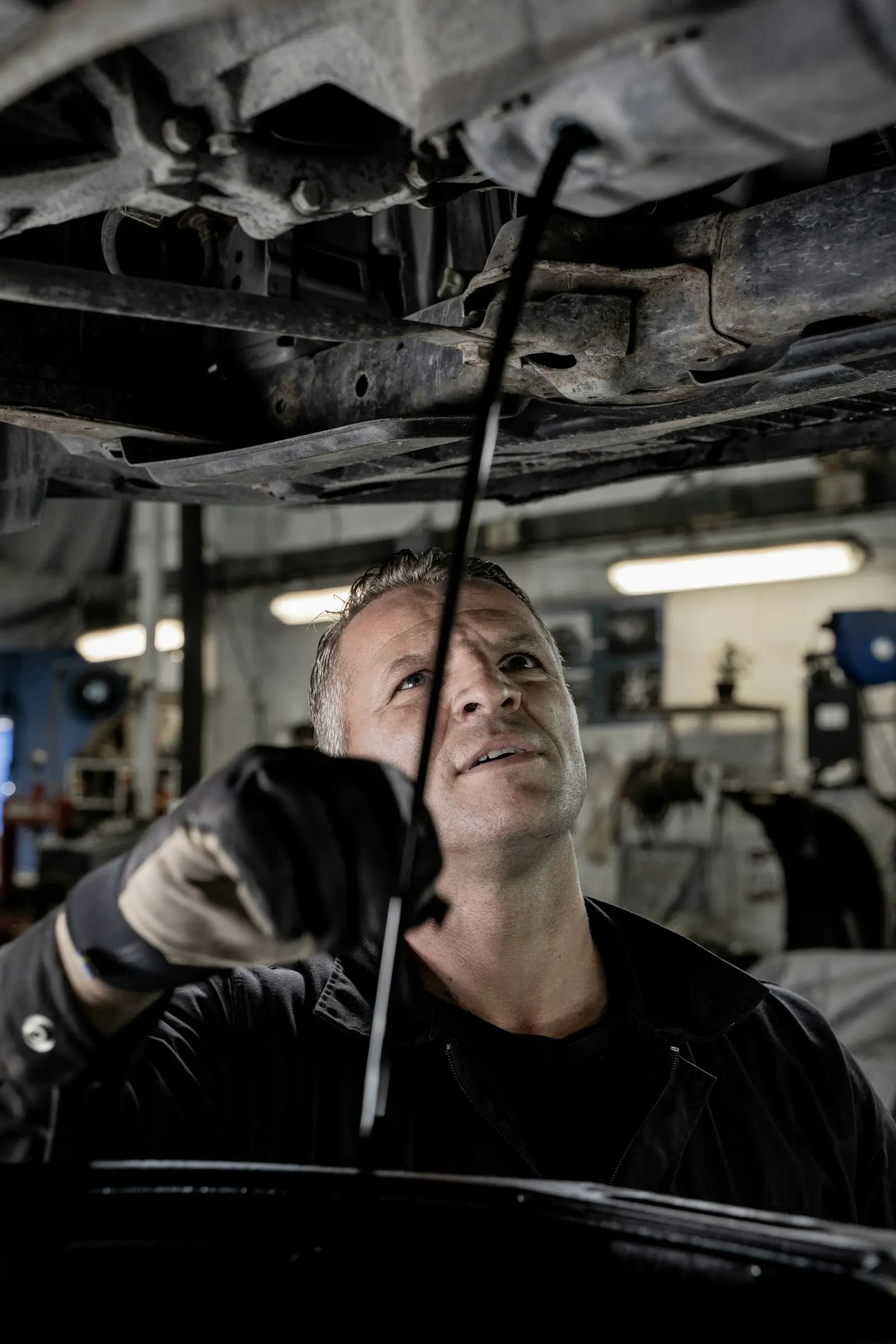 Technician inspecting the underside of a car on a lift